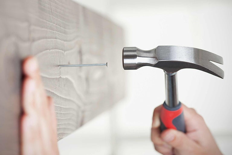 Ein Hammer schlägt einen Nagel in ein Holzbrett