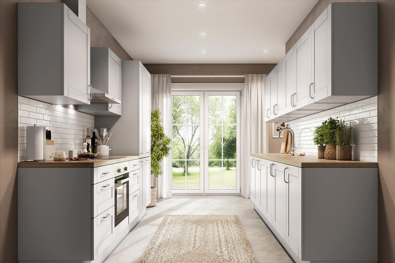 Moderne zweizeilige Küche mit weißen Rahmenfronten, Holzarbeitsplatten und weißem Fliesenspiegel. Hell mit Blick in den Garten.