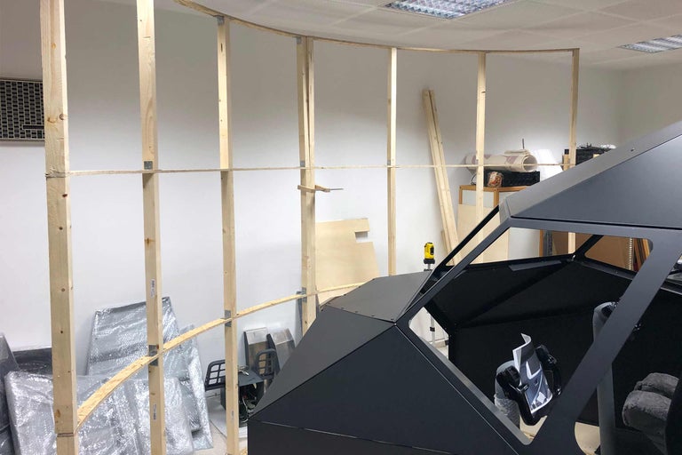 Innenausbau mit Holzrahmen und schwarzer Kabine in einem Raum.