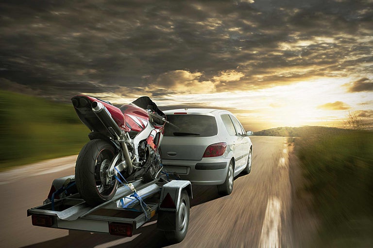 Voiture avec remorque et moto sur la route au coucher du soleil