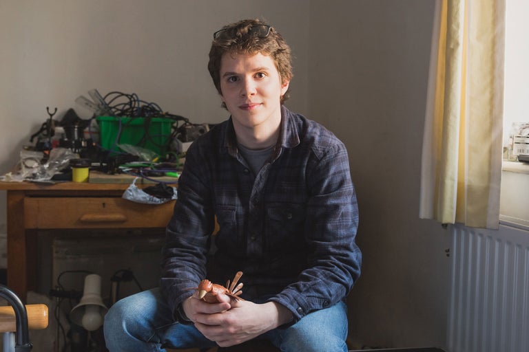 Porträt eines Mannes mit Holzfigurenvogel in einem Bastelraum