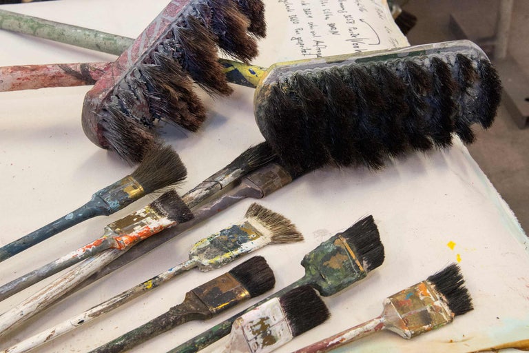 Plusieurs pinceaux usagés de différentes tailles et formes sont posés sur une surface.