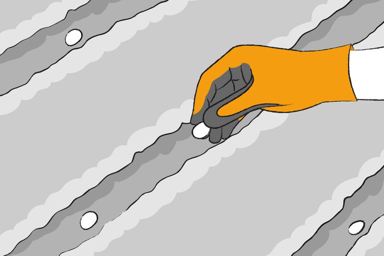 Hand mit Schutzhandschuh setzt Dämmstoffdübel in Dämmplatte