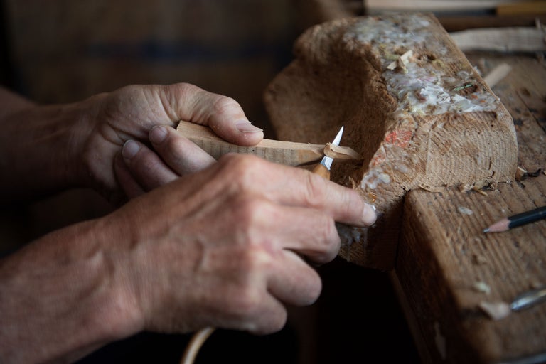 Gros plan d'une personne travaillant un morceau de bois avec un couteau à découper.