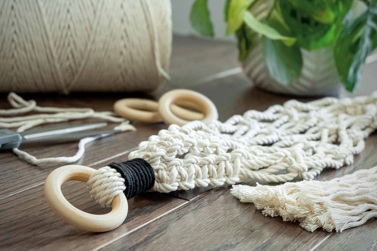 Suspension pour plantes en macramé, bobine de fil, ciseaux et plantes sur une table