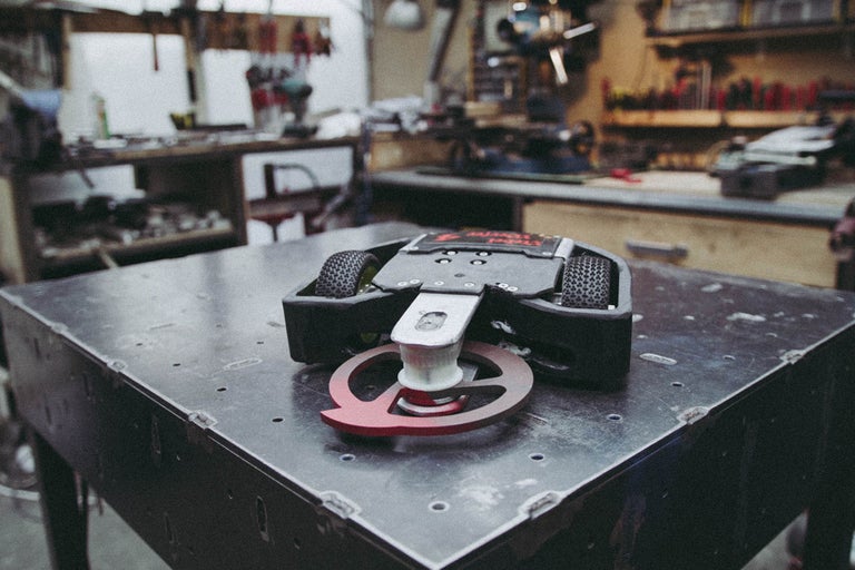 Robot avec roues et arme rotative sur une table dans un atelier.