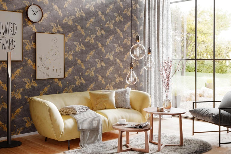 Salon avec papier peint à motifs, canapé jaune et tables en bois.