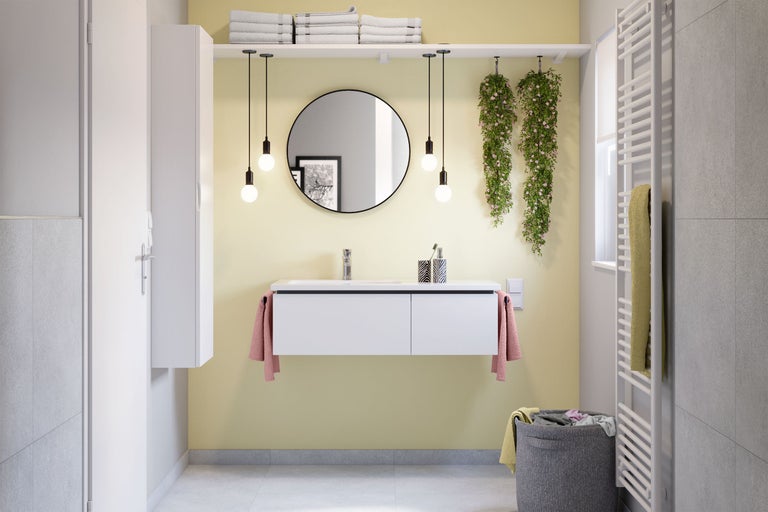 Modernes Badezimmer mit Waschbecken, Spiegel, Handtüchern, Heizkörper und dekorativen Elementen für eine helle und freundliche Atmosphäre.