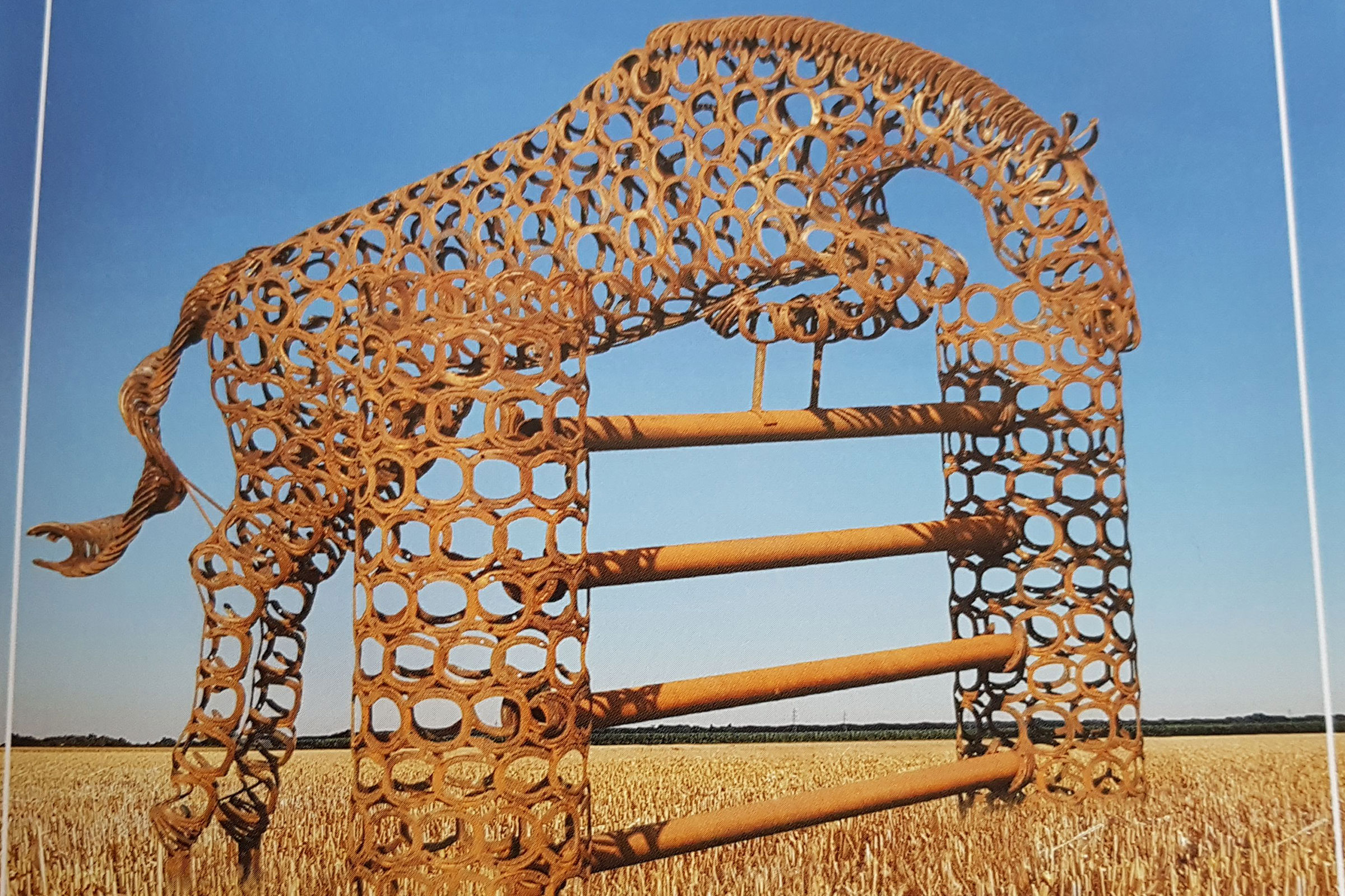 Sculpture de cheval en fers à cheval sautant par-dessus un obstacle, champ