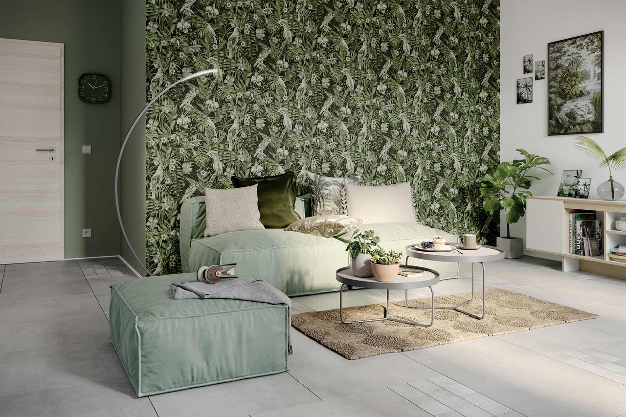 Salon avec papier peint jungle vert, canapé, pouf, tapis et tables d'appoint