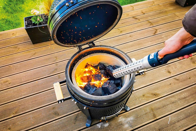 Barbecue ouvert au charbon de bois avec allume-feu sur une terrasse en bois