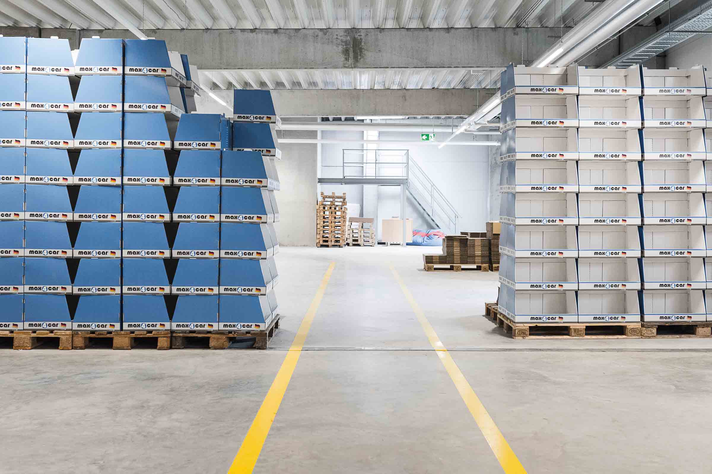 Entrepôt avec cartons MAX4CAR empilés sur palettes