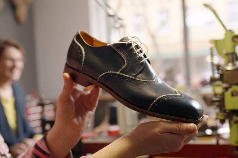 Chaussure bleue en cuir avec des lacets tenue à la main