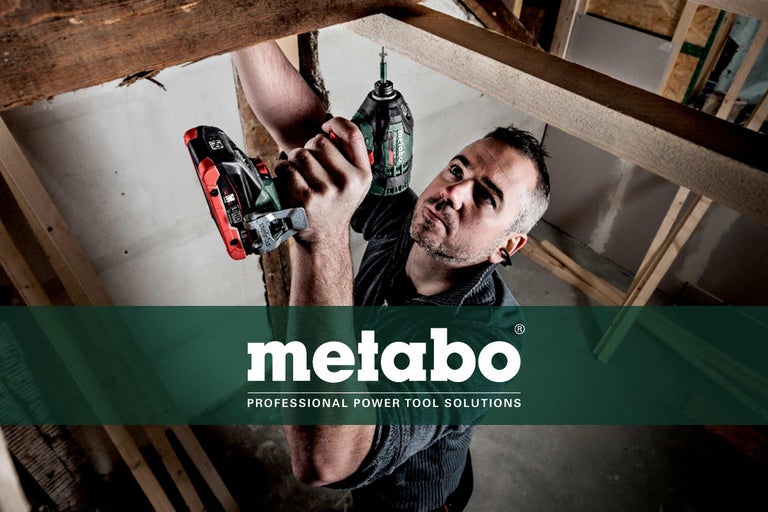 Artisan travaillant avec une visseuse à chocs sans fil Metabo sur des poutres en bois