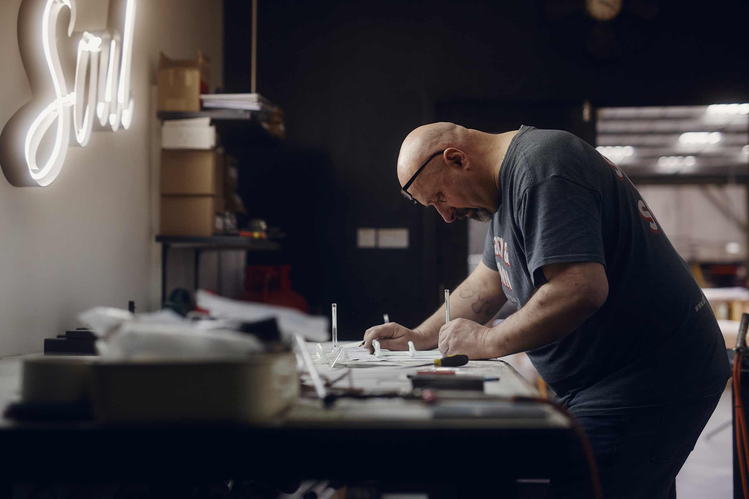 Artisan travaillant des lettres néon sur un établi