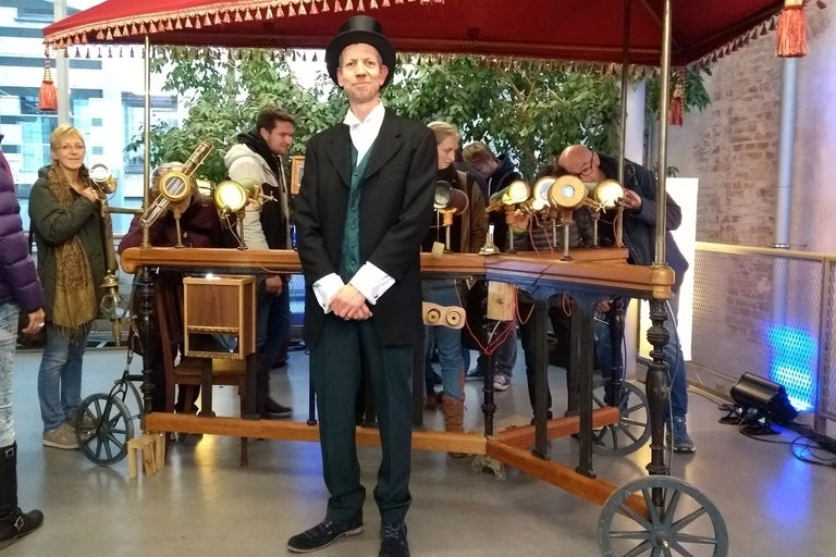 Homme en costume avec haut-de-forme debout devant un chariot avec des télescopes.
