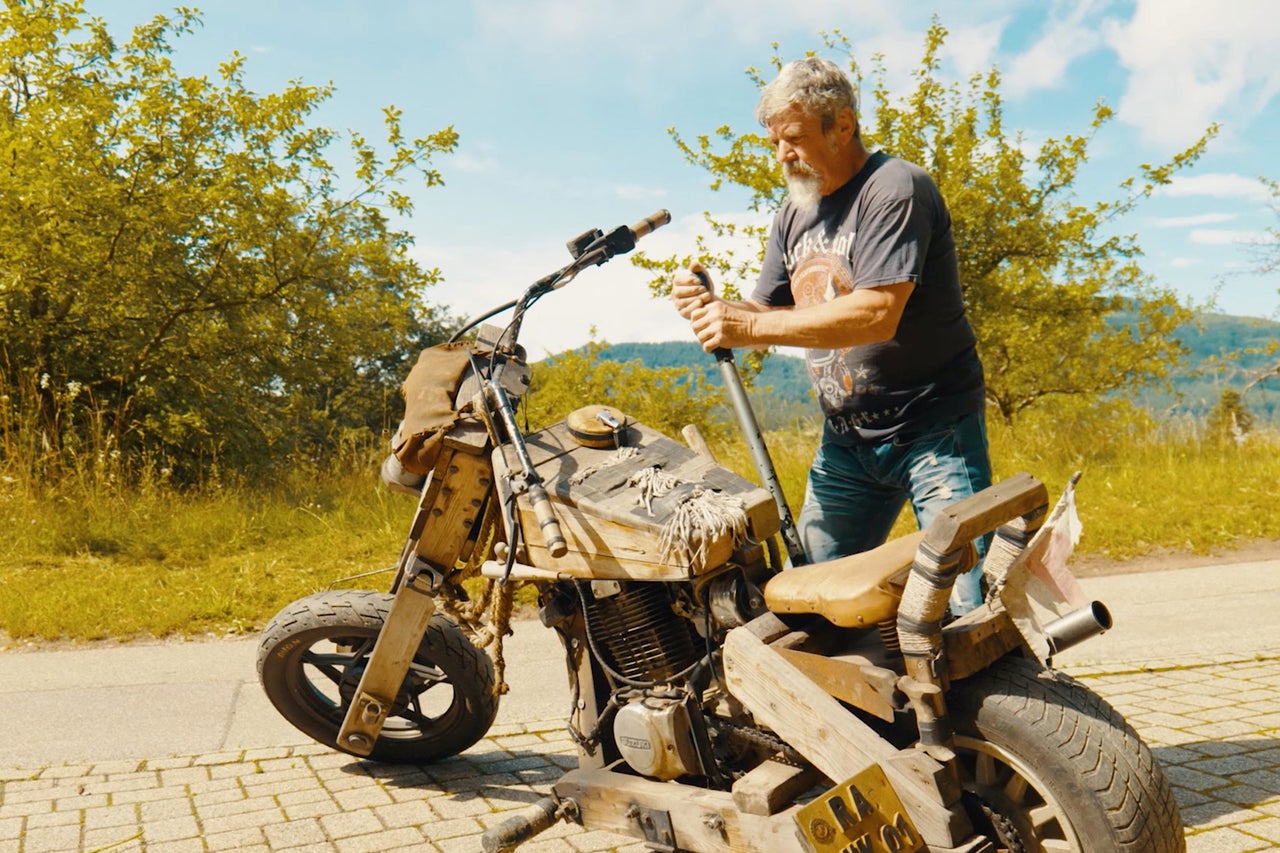 Homme avec moto sur le terrain. La moto est en bois.