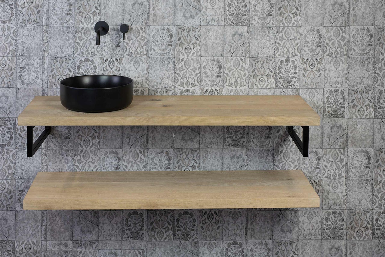 Waschbecken mit Holzbord und Wandarmatur vor gemusterter Wand