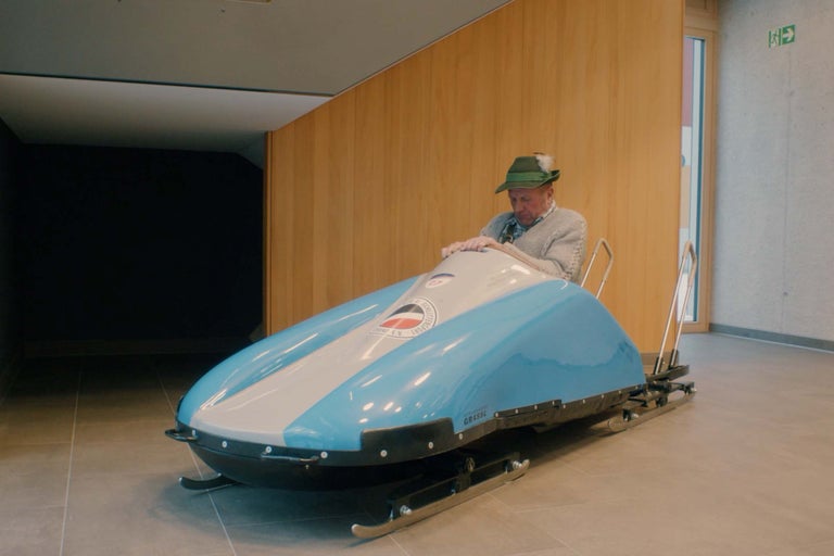 Un homme est assis dans un traîneau de course bleu et blanc à l'intérieur