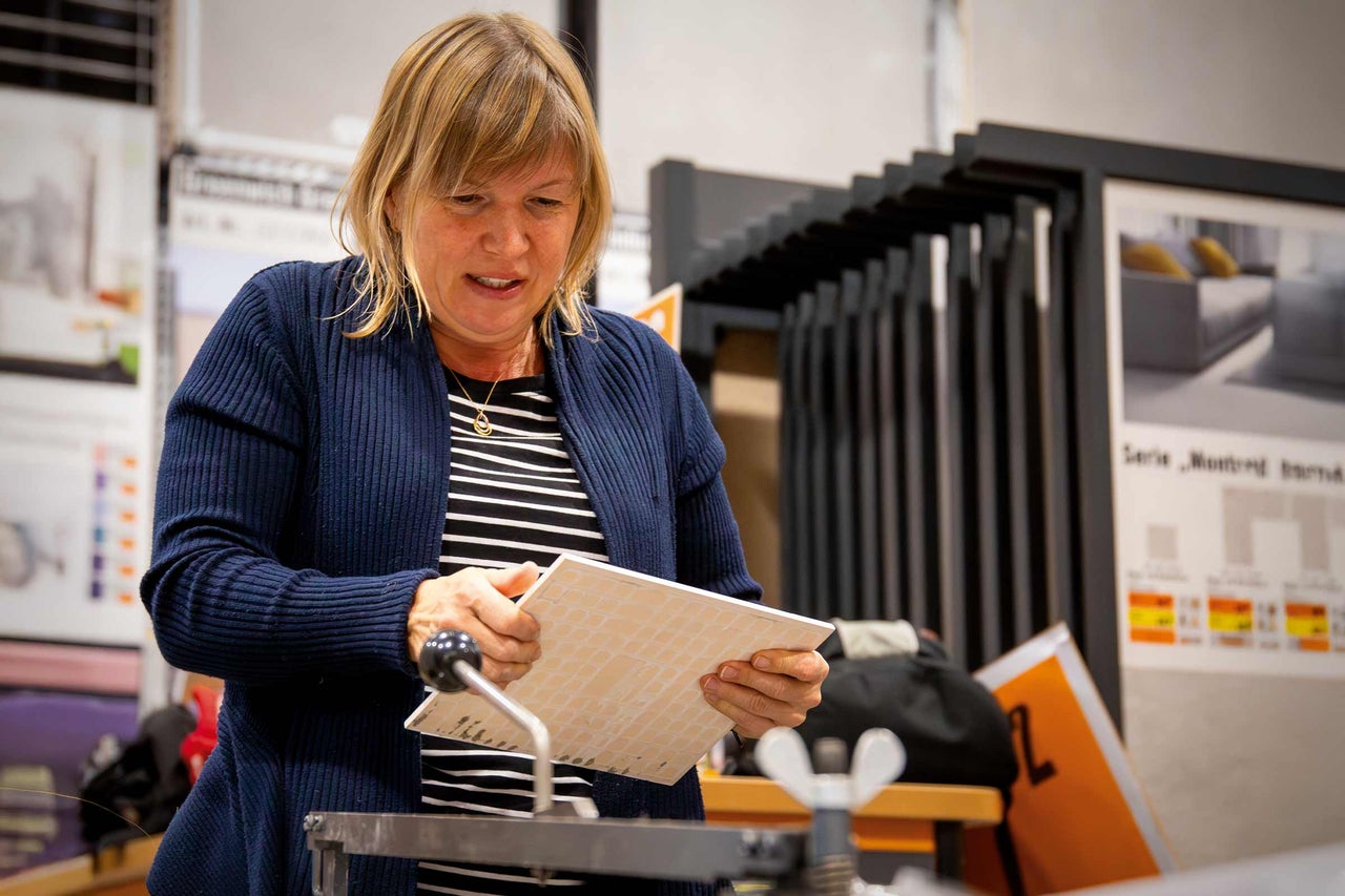 Une femme travaillant un carreau avec un coupe-carreaux.