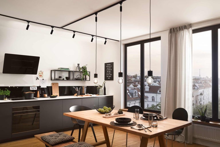 Helle Küche mit Esstisch, Küchenzeile, Pendelleuchten und Spots für die Deckenmontage.