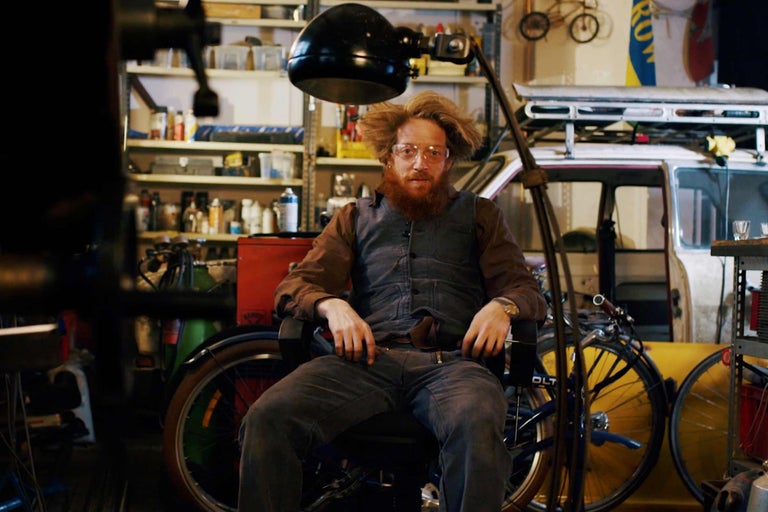 Scène d'atelier avec une personne assise, des vélos et des étagères