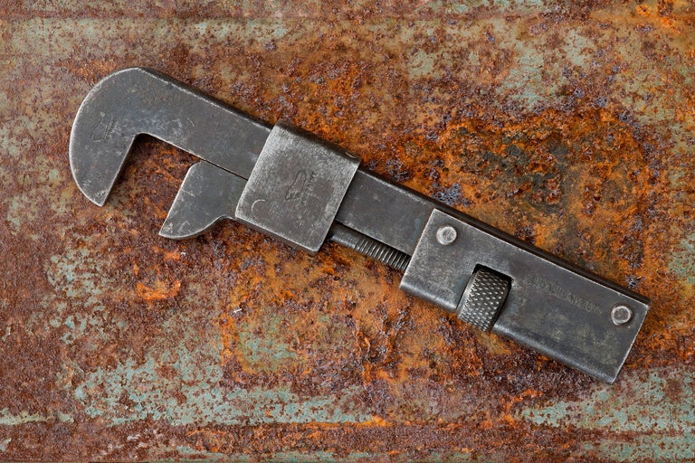 Verstellbarer Schraubenschlüssel aus Metall auf rostigem Hintergrund.