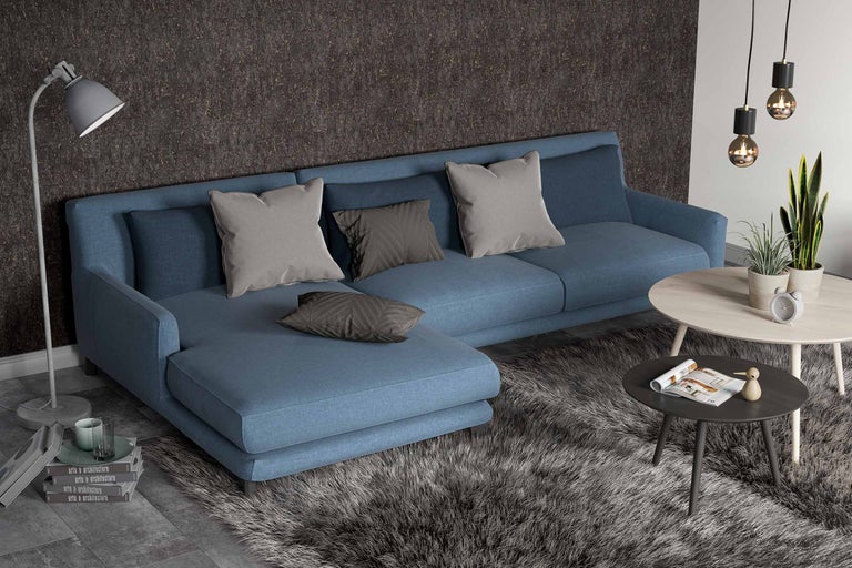 Wohnzimmer mit blauem Ecksofa, Kissen, Couchtischen, Stehlampe und Teppich