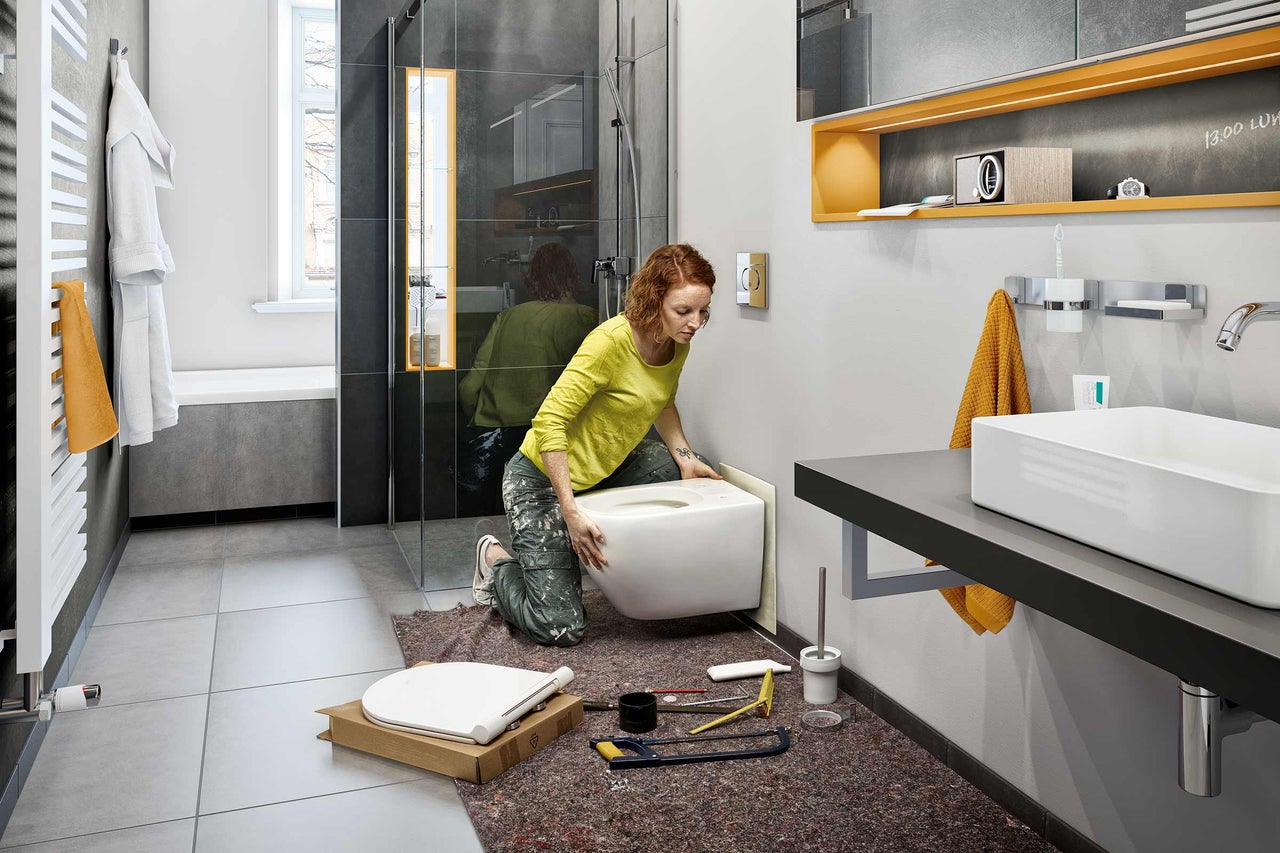 Frau installiert ein wandhängendes WC im Badezimmer.