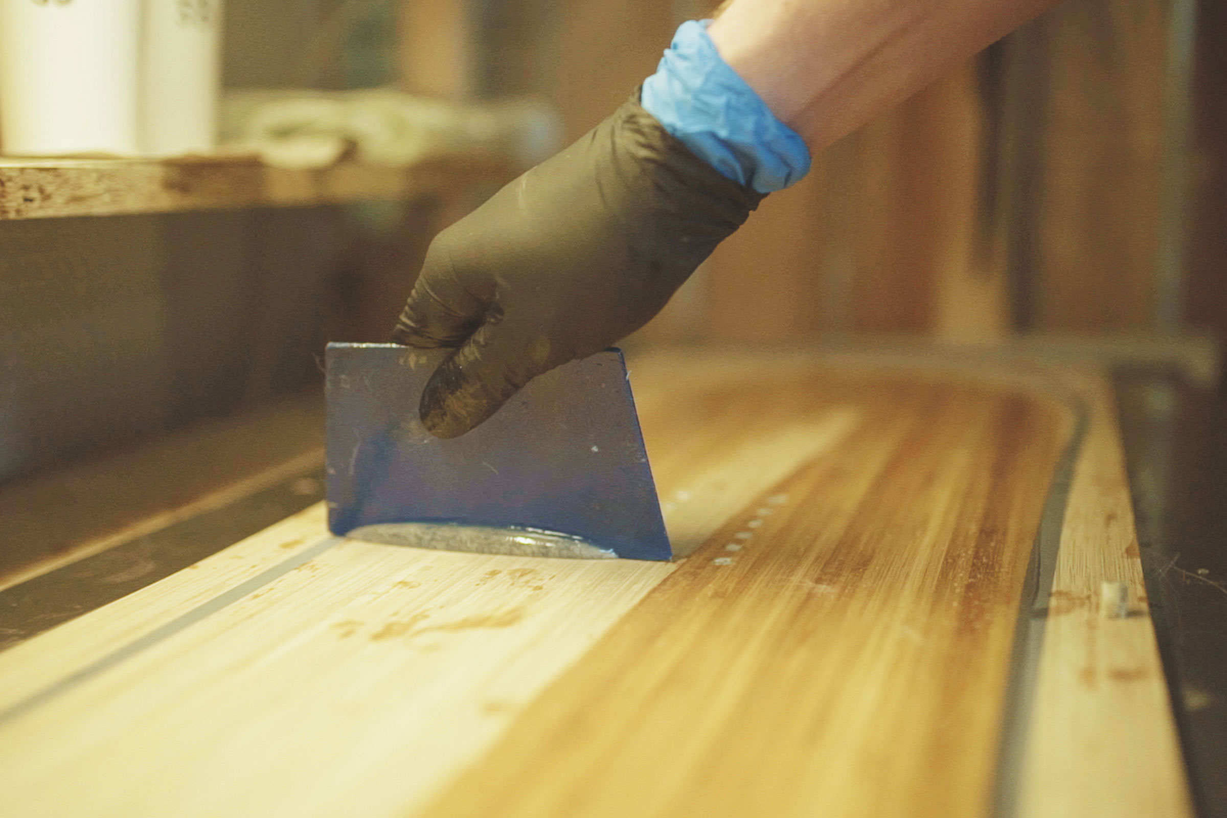 Auftragen von Epoxidharz auf ein Holzbrett mit einem Spachtel