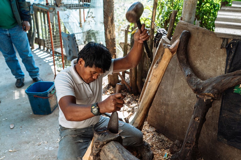 Homme travaillant le bois avec un marteau et un ciseau