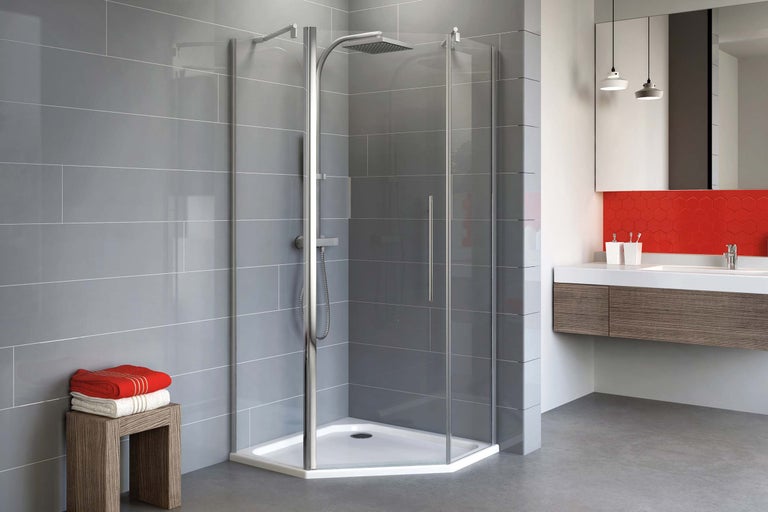 Helles Badezimmer mit einer Ecke Duschkabine, Waschtisch und grauen Fliesen.