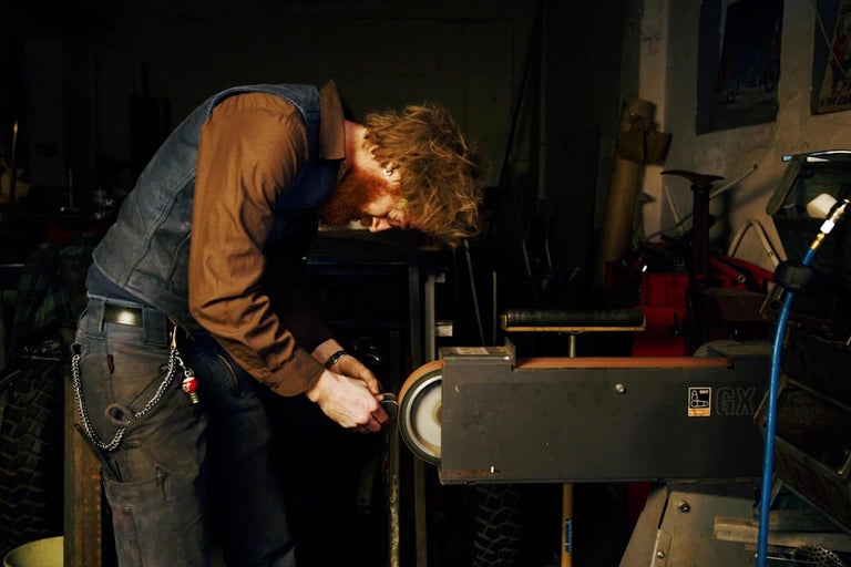 Un homme travaille avec une ponceuse à bande dans un atelier.
