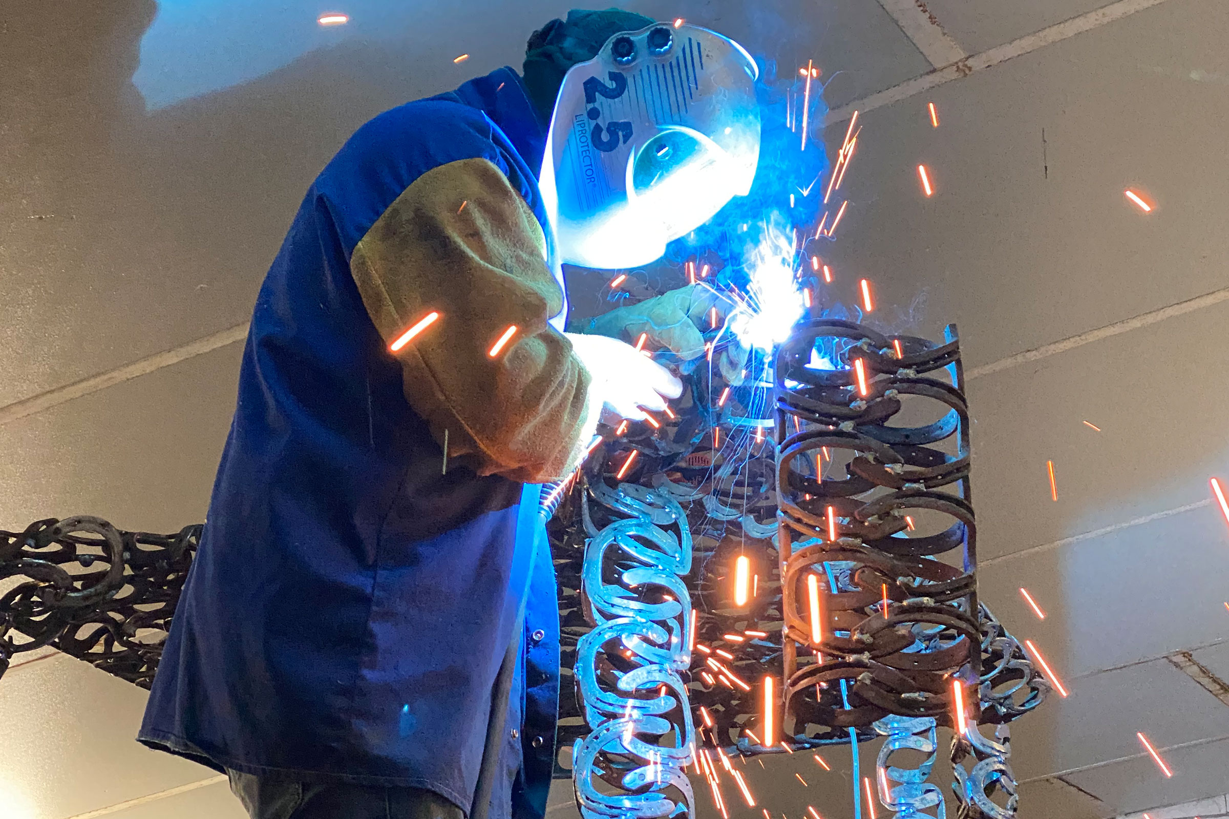 Soudeur travaillant sur une structure en fers à cheval.