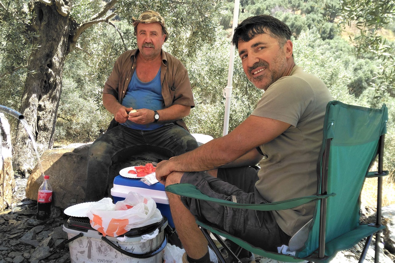 Deux hommes sont assis à l'extérieur avec une glacière et de la nourriture.