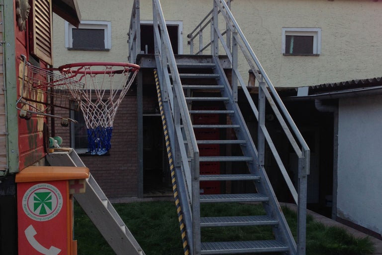 Aussenansicht eines Gebäudes mit Treppe und Basketballkorb