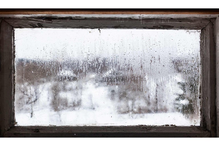Blick aus einem alten Fenster mit beschlagenem Glas auf eine verschneite Landschaft