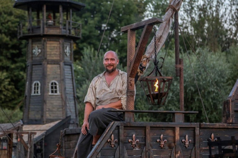 Scène avec un homme sur un bateau en bois et une tour en arrière-plan