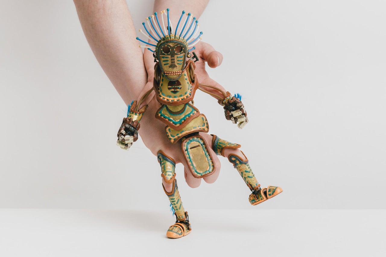 Main tenant une marionnette avec une coiffe de plumes