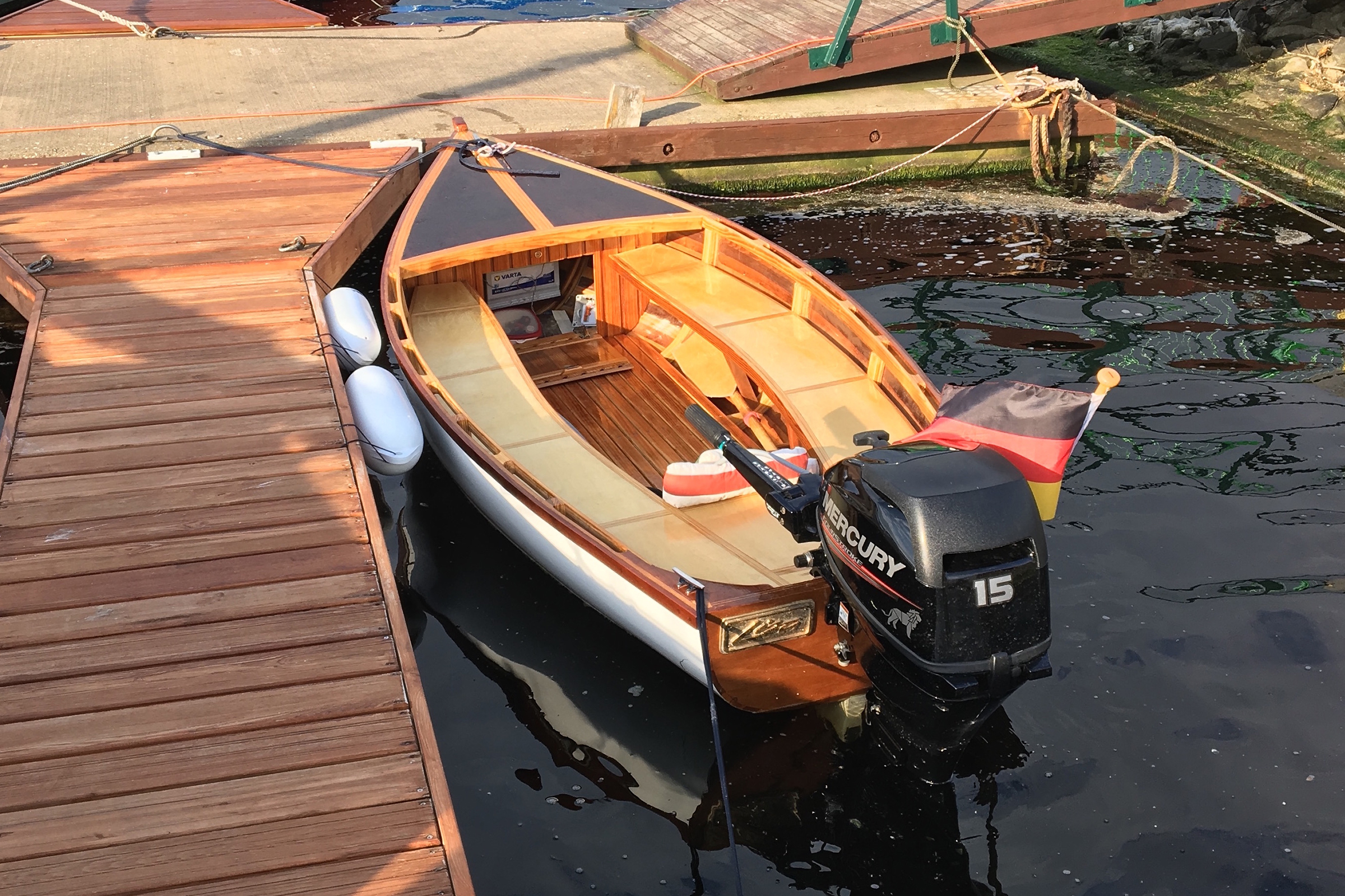 Holzboot mit Mercury Motor und Deutschland Flagge am Steg