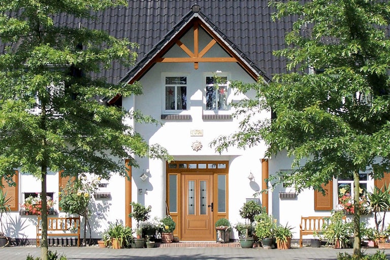 Ansicht eines Hauses mit Haustür, Fenstern und Pflanzen