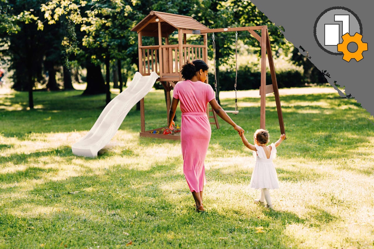 Tour de jeu en bois avec toboggan et balançoire dans un jardin avec une femme et un enfant.