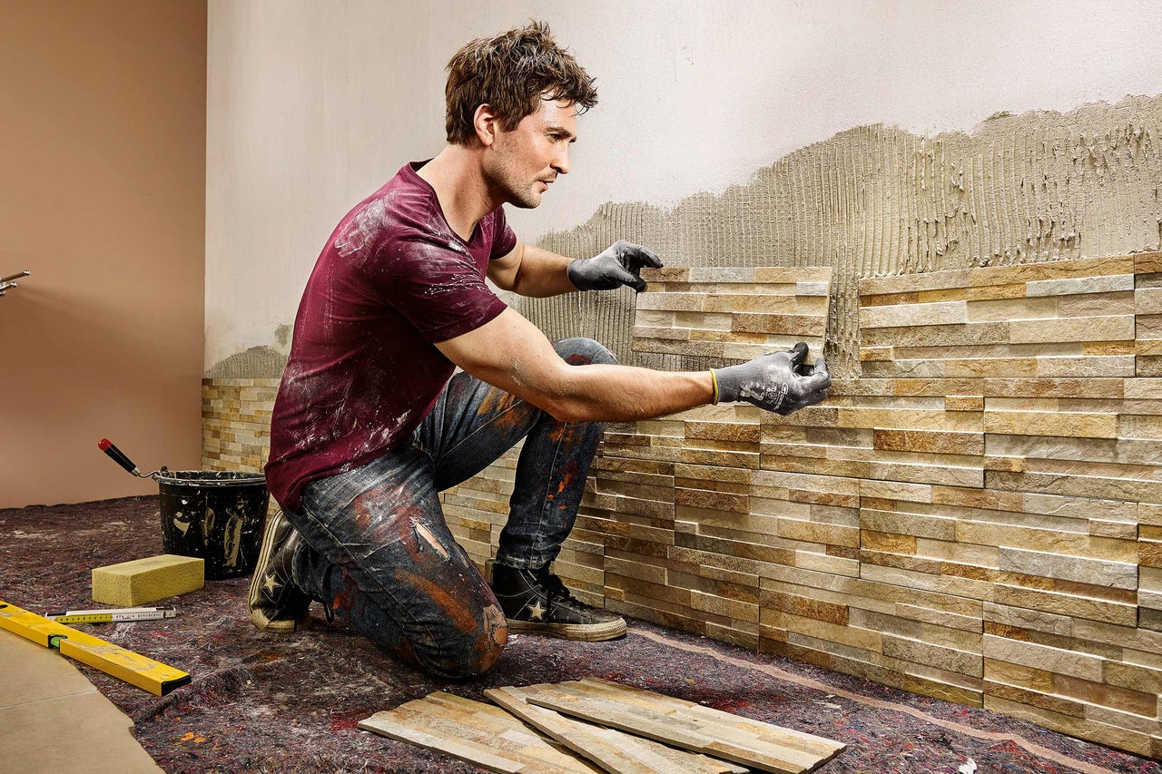 Artisan posant un revêtement mural en pierre naturelle à l'intérieur