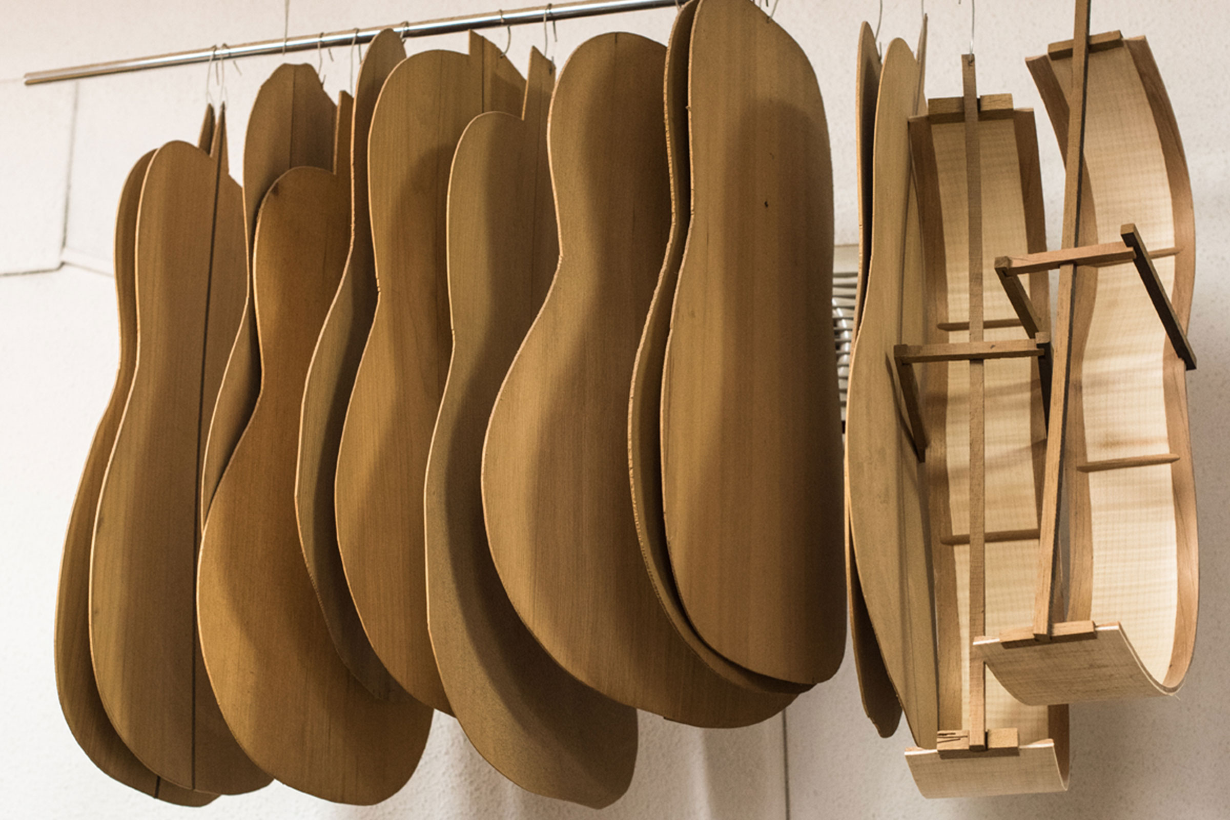 Plusieurs ébauches de guitare en bois suspendues à une barre.