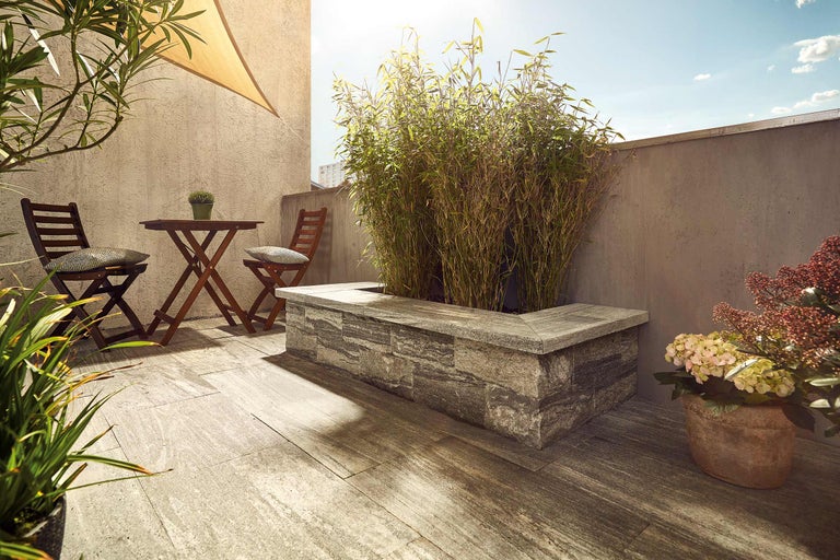 Terrasse avec plancher en bois, table et chaises et bac à fleurs avec plantations