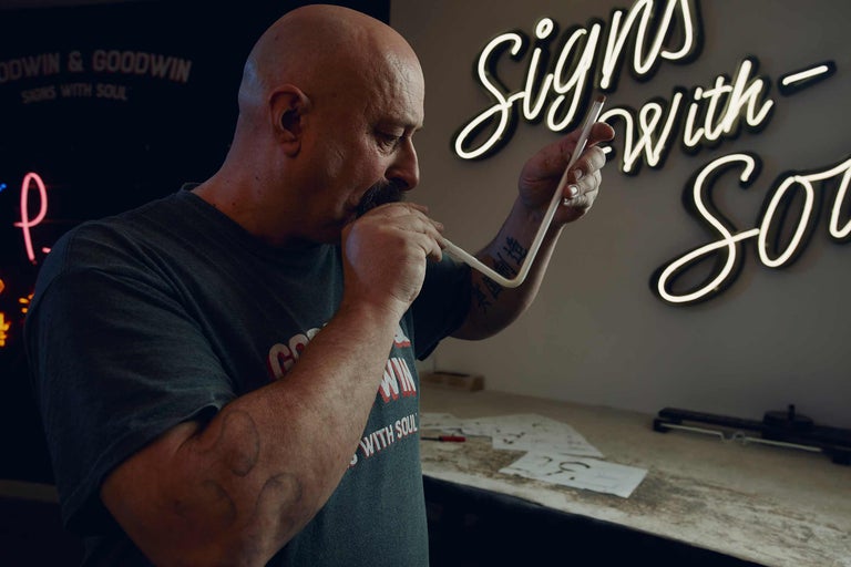 Un homme façonne un tube néon pour une enseigne lumineuse.