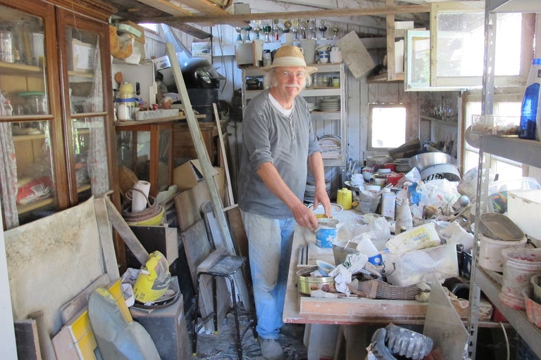 Homme avec un chapeau dans un hangar désordonné.