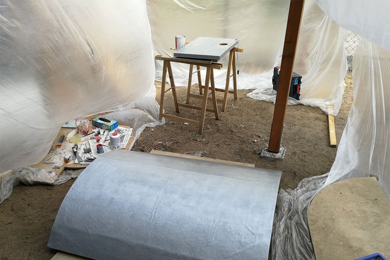 Scène avec outils et matériaux dans un espace recouvert de film plastique.