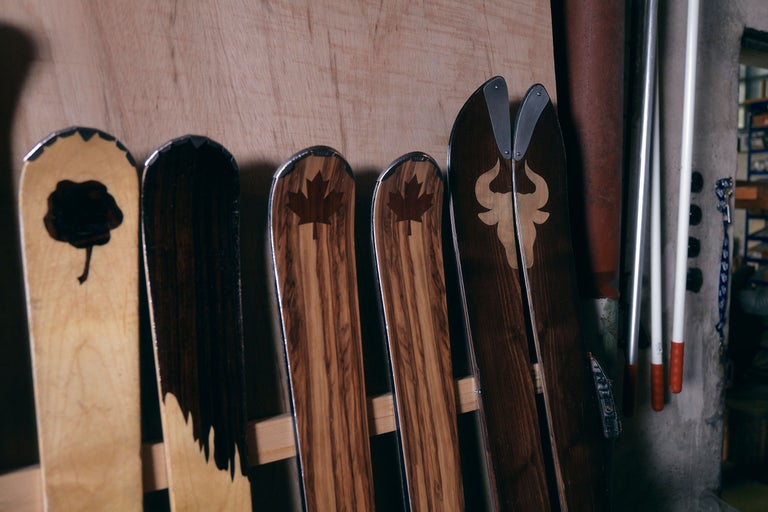 Plusieurs skis en bois avec différents motifs appuyés contre un mur.