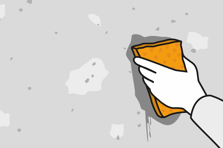 Main avec éponge nettoie le mur